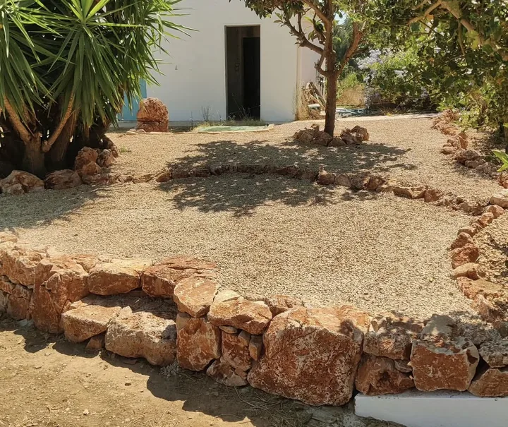Degraus em pedra natural e bordaduras baixas a separar níveis de jardim em gravilha junto a uma casa branca